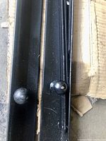 Close-up photo of two black metal rails with round knobs for Murphy bed frame.