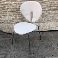 Front view of white chair showing seat and backrest padding, chrome legs, and overall modern design.