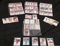 Multiple pages of 1970s hockey cards depicting players and team checklists laid flat on black cloth