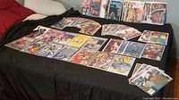 Photo showing a selection of comic books laid out on a black surface, including Wolverine, Vampire, and DC titles with colorful illustrated covers.