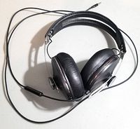 Black over-ear wired headphones folded with visible leather ear pads and metal frame, cable and 3.5mm jack visible.