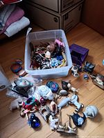 Top view of the lot showing plastic bin with numerous small animal figurines inside and several placed outside the bin on the floor