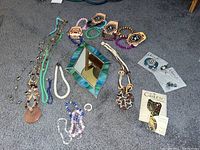 Photo showing multiple mala bead bracelets, various beaded necklaces, a small stained glass mirror with blue-green border, Celtic harp brooch card, and Celtic card with harp pins.