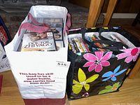 Two reusable bags filled with assorted DVDs showing various titles on top.