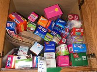 Top view of kitchen storage and packing materials in a cabinet, showing various boxes of Ziploc bags, Hefty freezer bags, paper lunch bags, and foil bags.
