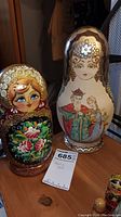 Two large Matryoshka dolls showing floral and character designs with a Maxsold sticker for scale