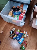 Wooden Matryoshka nesting dolls in and around a plastic storage bin on wooden floor