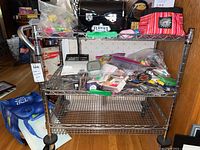 Full view of the 3-tier rolling metal wire shelf loaded with miscellaneous items (not for sale).