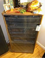 Full view of Sony SU-S3010 wood stereo cabinet with glass front door closed, housing multiple Sony audio components inside, with miscellaneous decorative items on top.