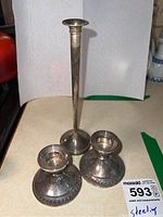 Three sterling silver candle holders shown together, one tall and two shorter with decorative bases.