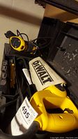 Two yellow and black DeWalt power tools including an electric reciprocating saw and other tool in their black plastic carrying cases.