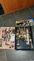 Photo showing multiple trays filled with forks, spoons, knives, openers, and cutters made of stainless steel and silverplate. Items show tarnish and scratches.