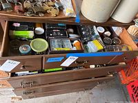 Photo of the top drawer showing assorted hardware items in jars, boxes and loose compartments