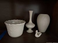 Four white Lenox porcelain pieces displayed: two vases, planter, and swan figurine.