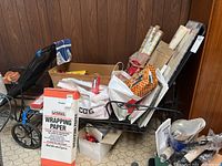 Heavy metal outdoor chaise lounge chair in black with an adjustable backrest and wheels for mobility. Various bags and packing papers are around it.