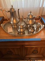 Full view of seven piece pewter tea set including coffee pot, teapot, sugar bowl with lid, creamer, tray, and small accessory items.