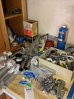 View of assorted plumbing parts including pipe fittings, connectors in metal and plastic, valves, and an unopened propane torch kit in a garage setting.