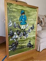 Full view of framed painting showing child in blue coat surrounded by pigeons on a green background
