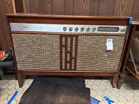 Front view of Silvertone console stereo showing its wooden cabinet, fabric speaker covers, control knobs, and tuning display.