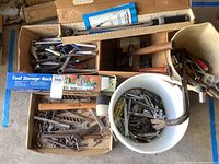 Top view of assorted hand tools including a hammer, wrenches, various hardware items in boxes and buckets.