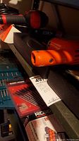 Shelved power tools with drill bits in packages below. Orange Black & Decker drill visible.