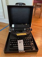 Black Remington Rand vintage typewriter in an open black carrying case, showing the full item and case interior.