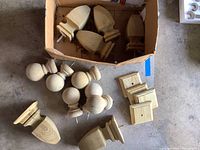 Overview of wooden ball, gothic, and square post caps in a garage setting, some still inside boxes.