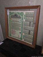 Framed railroad bond certificate with wooden frame and plexiglass, showing overall view.