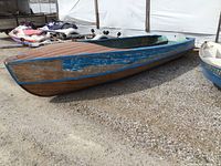 Starboard side view showing hull shape, partially stripped blue paint over cedar strips