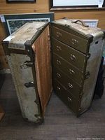 Photo showing trunk opened to reveal 5 drawers inside in a vertical wardrobe style.
