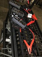 Three NOCO Genius Boost portable battery jump starters on a black metal surface, two GB40 models and one GB20 model with red clamps attached.