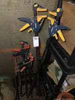 Photo shows 2 large Mastercraft quick clamps with yellow and black handles together with other smaller clamps.