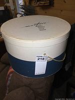 Closed round storage box with 'Martins' logo on lid, blue and white two-tone with rope handle.