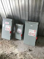 Three gray metal Cutler Hammer electrical disconnect panels standing on floor, labeled 'Main Disconnect Switch' and other switch descriptions.