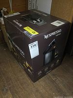 Box of the Nespresso Vertuo coffee machine by DeLonghi, showing full packaging with product image and branding.