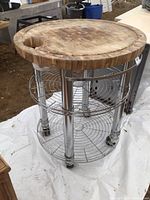Full view of round butcher block prep table showing wood top, chrome legs, wire shelves, casters