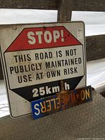 Photo of the large stop sign showing the caution message about the road not being publicly maintained, with '25 km/h maximum' speed limit.