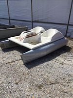 Angled side view of SeaRider two-seat pontoon pedal boat hull with aluminum pontoons at storage yard