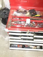 Red steel toolbox top tray open showing assorted shallow and deep sockets.