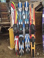 Four water skis displayed upright showing color and branding details.