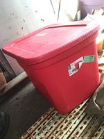 Closed large red plastic storage bin containing welding gear and tools.