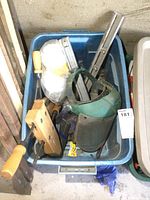 Blue bin containing wooden hand clamps, metal wood vise, green face shield, and white disposable masks in plastic bags.