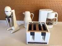 Full lot showing Hamilton Beach milkshake mixer with stainless steel mixing cup, white drink carafe, Toastmaster 4-slice toaster, and Krups coffee maker with glass carafe.