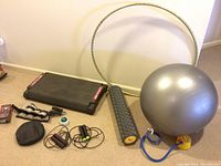 Full view of aerobic step platform, yoga ball, hoop, foam roller, jump ropes, and small accessories arranged on carpet.