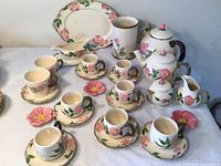 Overall display of cups, saucers, teapots, platter, gravy boat, creamer, sugar bowl, utensil holder and spoon rests