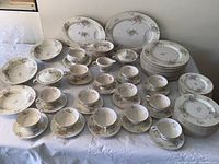 Full view of the entire Theodore Haviland Apple Blossom china set with multiple plates, cups, bowls, and serving pieces displayed on a table.