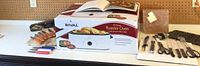 Rival 18 Quart Roaster Oven in box with accessories and knife set laid out on a tabletop.