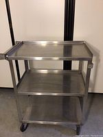 Front view of the Lakeside stainless steel rolling kitchen cart showing three shelves and caster wheels.