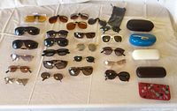 Full view of all sunglasses laid out on a table with cases on the right side showing variety of styles and colors