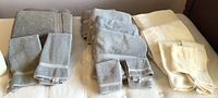 Three sets of towels including two gray sets and one cream set, showcasing the quantity and color differences of each set.